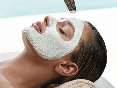 Frau mit Gesichtsmaske auf Massageliege