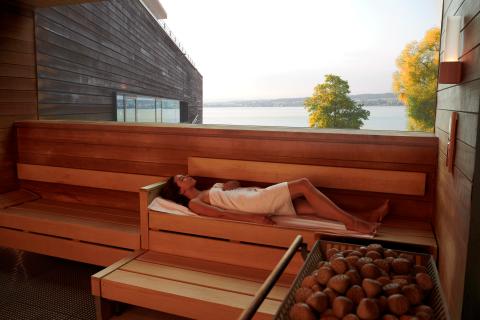 Frau liegend in der Panoramasauna mit Blick über den See